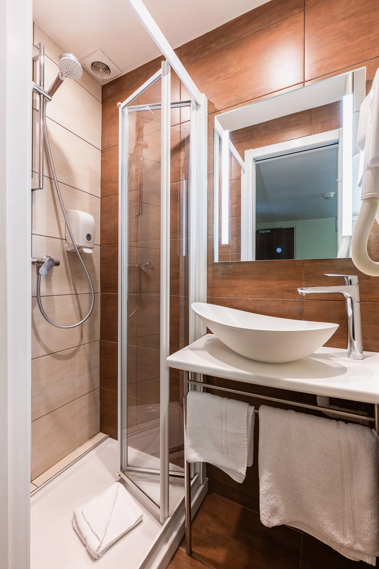 Salle de douche avec vasque blanche, miroir lumineux et carrelage imitation bois