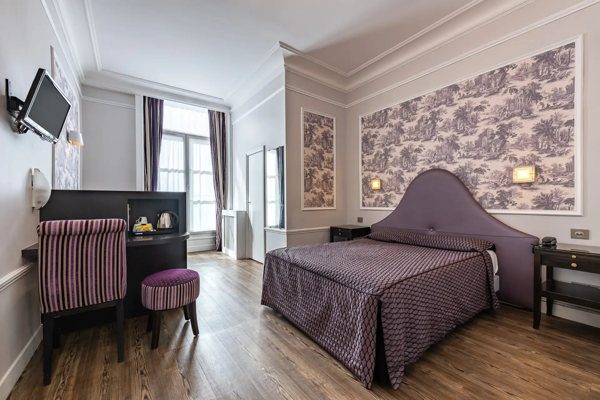 Chambre triple avec lit double, bureau noir, chaise rayée et télévision murale