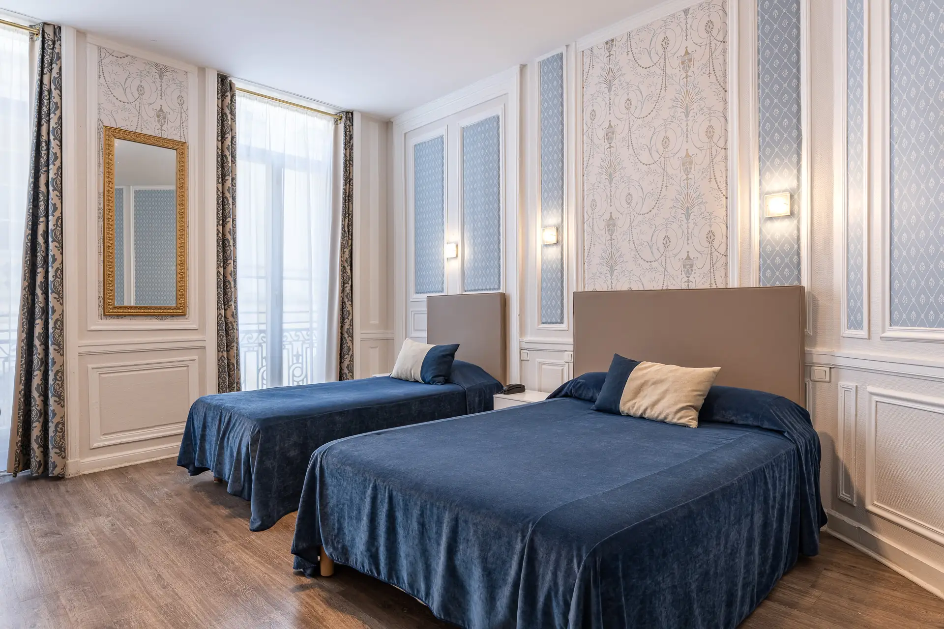 Chambre triple avec un lit double et un lit simple aux couvre-lits bleu nuit, boiseries claires