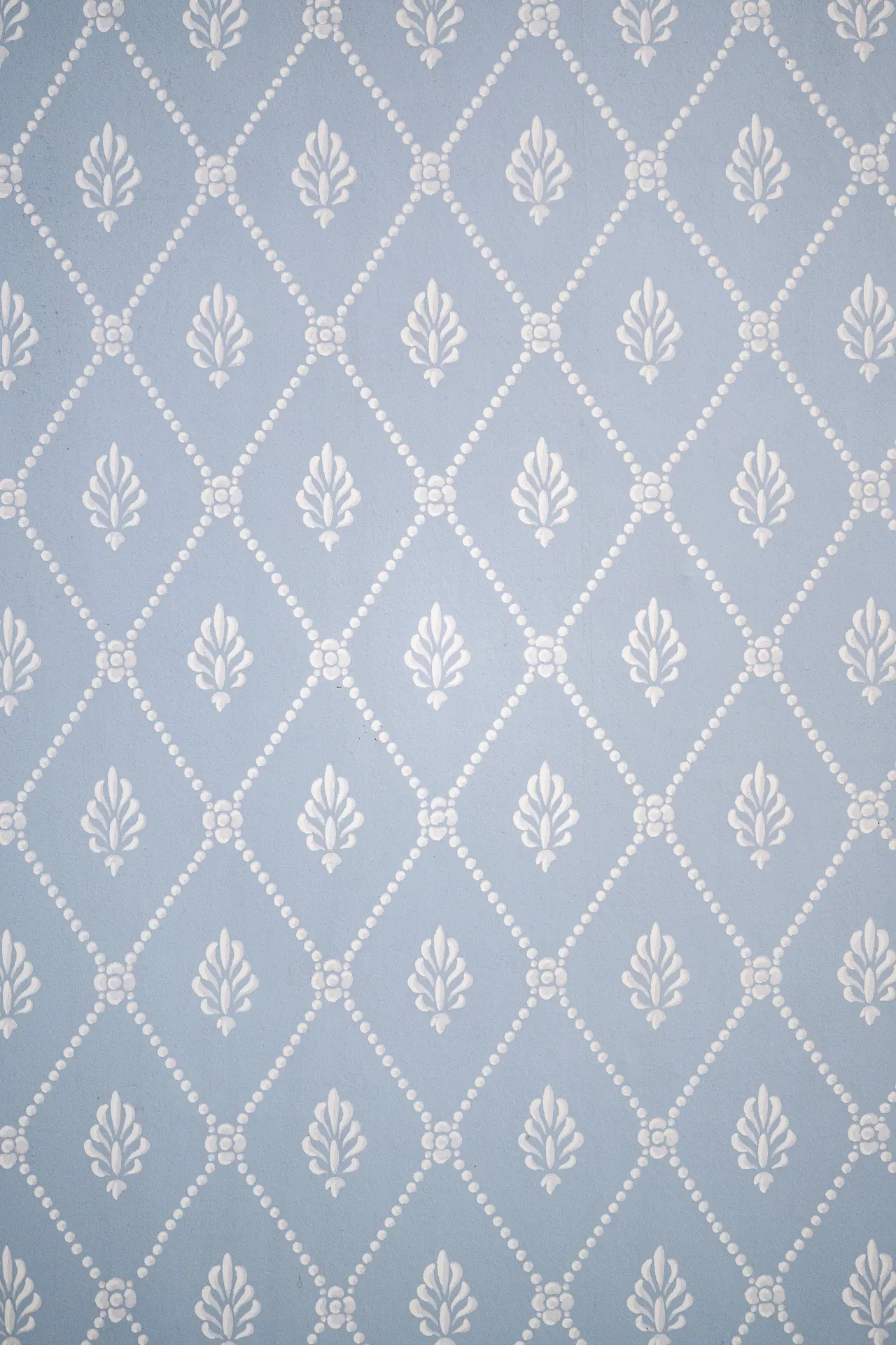 Papier peint bleu ciel à losanges perlés et palmettes blanches